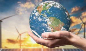 Image of person holding earth with windmills in the background for story on FireKeepers Casino committing to using 100% renewable energy