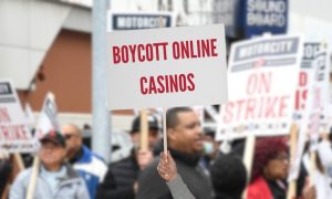 The words "boycott online casinos" on a blank sign in front of image of striking Detroit casino workers for a story on those workers calling for a boycott of Detroit casinos' online platforms