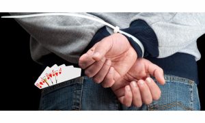 Man with hands zip-tied behind his back and playing cards sticking up from his back pocket. A Michigan poker champ says he was abducted and extorted for his gambling winnings. The FBI is investigating.