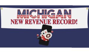 Banner reading "Michigan - New Revenue Record" hangs over a mobile phone showing casino icons. Online casinos set another new Michigan monthly revenue record in January with $181.9 million, bypassing the previous record set in December.