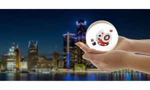 Hands holding a glowing crystal ball with casino symbols inside of it in front of the skyline of Detroit. The latest economic projections for Detroit show improved wages and a decline in unemployment. That could lead to improved casino revenue.