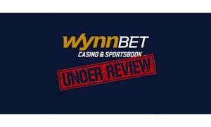 WynnBet casino and sportsbook logo on a navy background with the large red stamp reading "Under Review" on top to indicate that the operator's Michigan online casino will continue doing business for now.