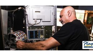 Man fixing and testing a slot machine. The MGCB Gaming Lab Manager Robert Franklin recently discussed how fair gambling is ensured for Michigan casino patrons.