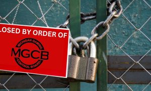 Chain link fenced locked with a chain and large padlock. There is a red sign hanging from the fence reading "Closed By Order Of" with the logo of the Michigan Gaming Control Board. Linos Antonio Kas-Mikha and Robert Jamerson each face four felony charges for allegedly operating an illegal storefront casino in Flint.