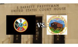 Flag of the sault ste. marie tribe of chippewa indians flag and the logo of the US Department of the Interior over a background of The E. Barrett Prettyman United States Court House in Washington, DC. The tribe is seeking a court ruling to build 2 Michigan casinos.