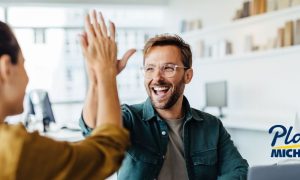 Two businesspeople high-five. Lawmaker Shawn Fluharty has addressed nationwide issues such as cannibalization and illegal gambling — two areas where Michigan excels.