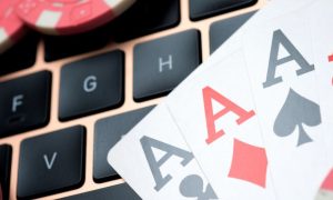 Poker chips and four aces are laid on a computer keyboard to signify online poker. Just in time for the 2024 World Series of Poker, WSOP is expected to launch multi-state poker pools between Michigan, New Jersey and Nevada.
