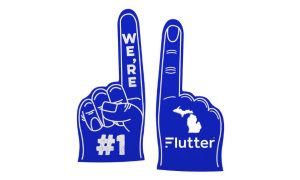 Two blue foam fingers. The first says #1, the second has the Michigan outline and the Flutter logo. Purchasing PENN would give FanDuel's parent company a 46% and 29% share of Michigan's sports betting and online casino markets, respectively.