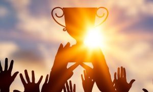 Hands reaching for a trophy. The MCGB has worked hard to curb illegal gambling, which has made it a finalist for the 2024 Global Regulatory Awards.