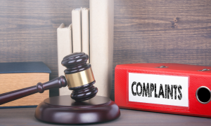 a gavel next to a folder with complaints labeled on it