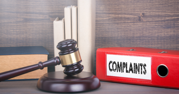 a gavel next to a folder with complaints labeled on it