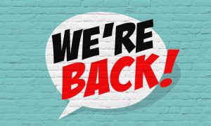 a we're back quote symbol painted over a brick wall