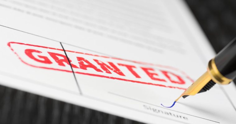 a document stamped granted while a pen signs on the form