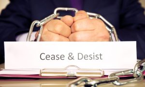 a man's hands chained together with a cease and desist sign in front of him