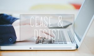 a person using a laptop computer with the words cease and desist imposed over it