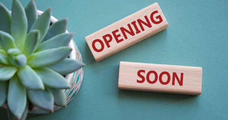 a pair of tiles spelling opening soon next to a plant