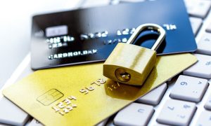 Gold padlock securing two credit cards on a keyboard