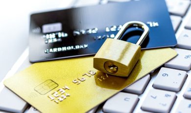 Gold padlock securing two credit cards on a keyboard
