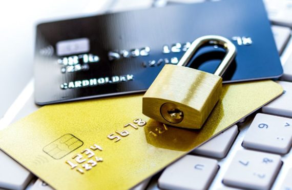 Gold padlock securing two credit cards on a keyboard