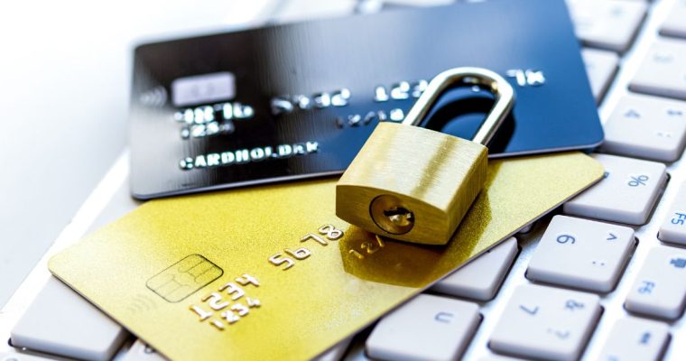 Gold padlock securing two credit cards on a keyboard