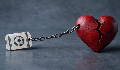 A metal chain connects a paper ticket with a soccer ball illustration to a large red broken heart.